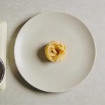 Assiette vue de dessus avec petite portion de pates et balance de cuisine
