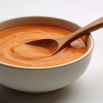 Bol de soupe orange cremeuse avec cuillere en bois