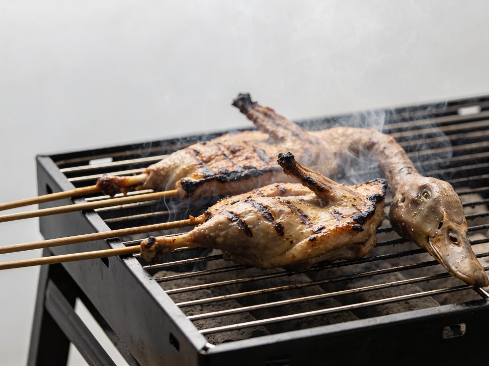 Brochettes de canard grillees sur barbecue fumant