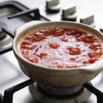 Casserole de sauce tomate bouillante sur cuisiniere