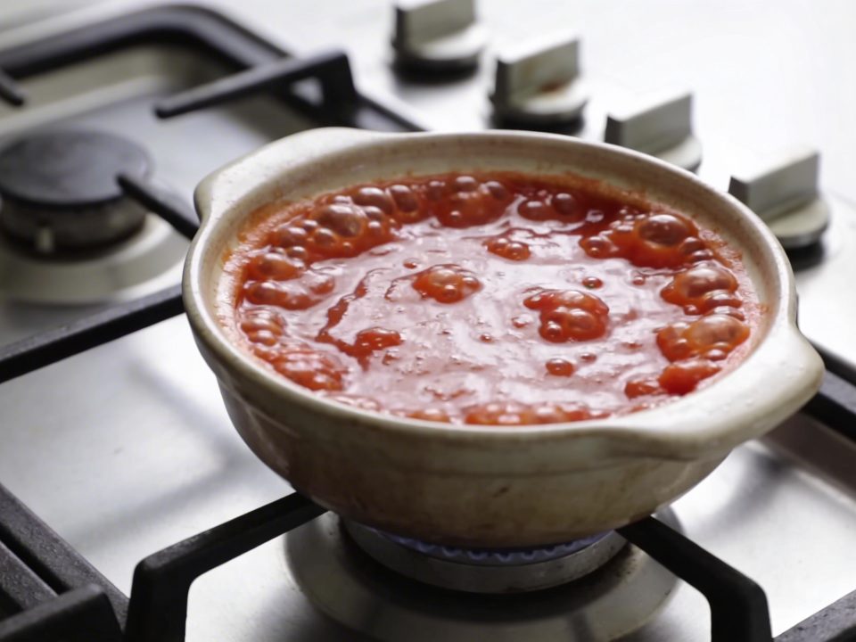 Casserole de sauce tomate bouillante sur cuisiniere
