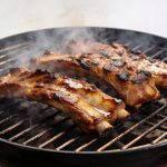 Cotes de porc marinees grillees sur barbecue fumant