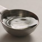 Cuillere doseuse en metal remplie d eau