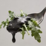 Cuillere nappant salade de roquette avec creme sombre