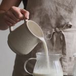 Femme versant lait chaud dans pots en verre