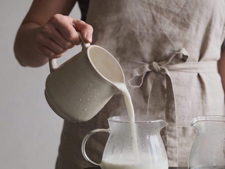 Femme versant lait chaud dans pots en verre
