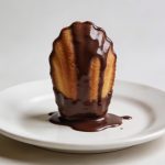 Madeleine trempee dans chocolat brillant sur assiette
