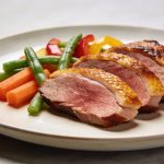 Assiette de magret de canard tranche avec legumes colores