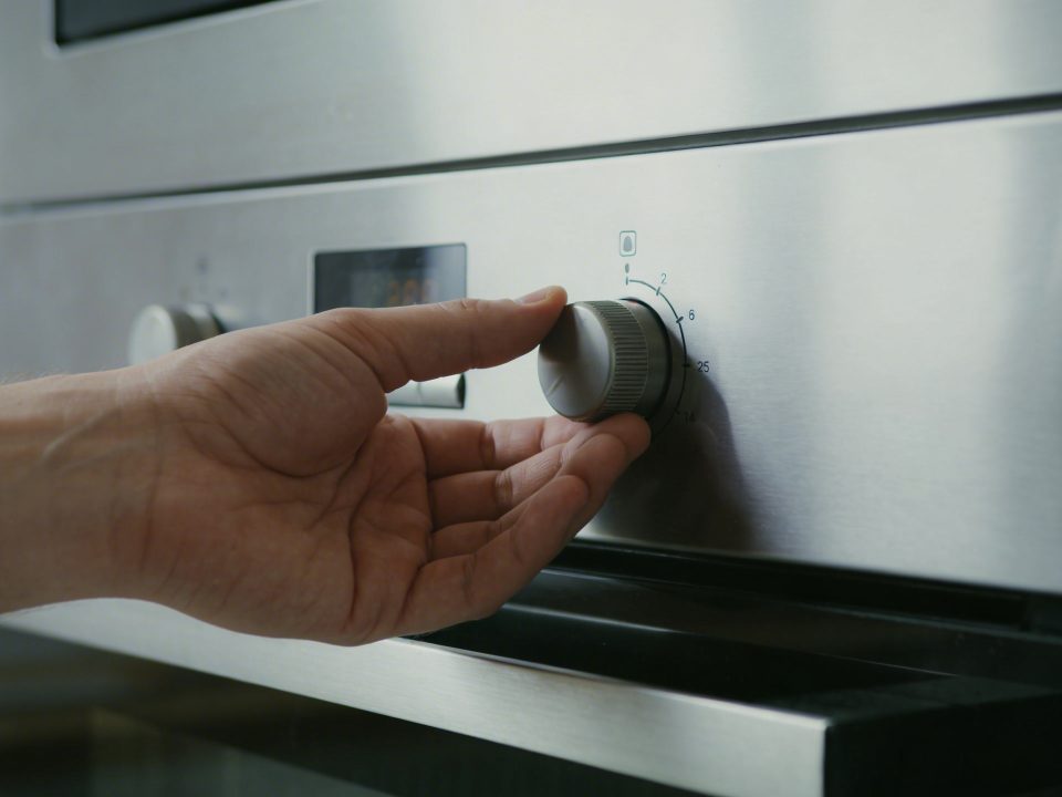Main ouverte ajustant thermostat de four brillant