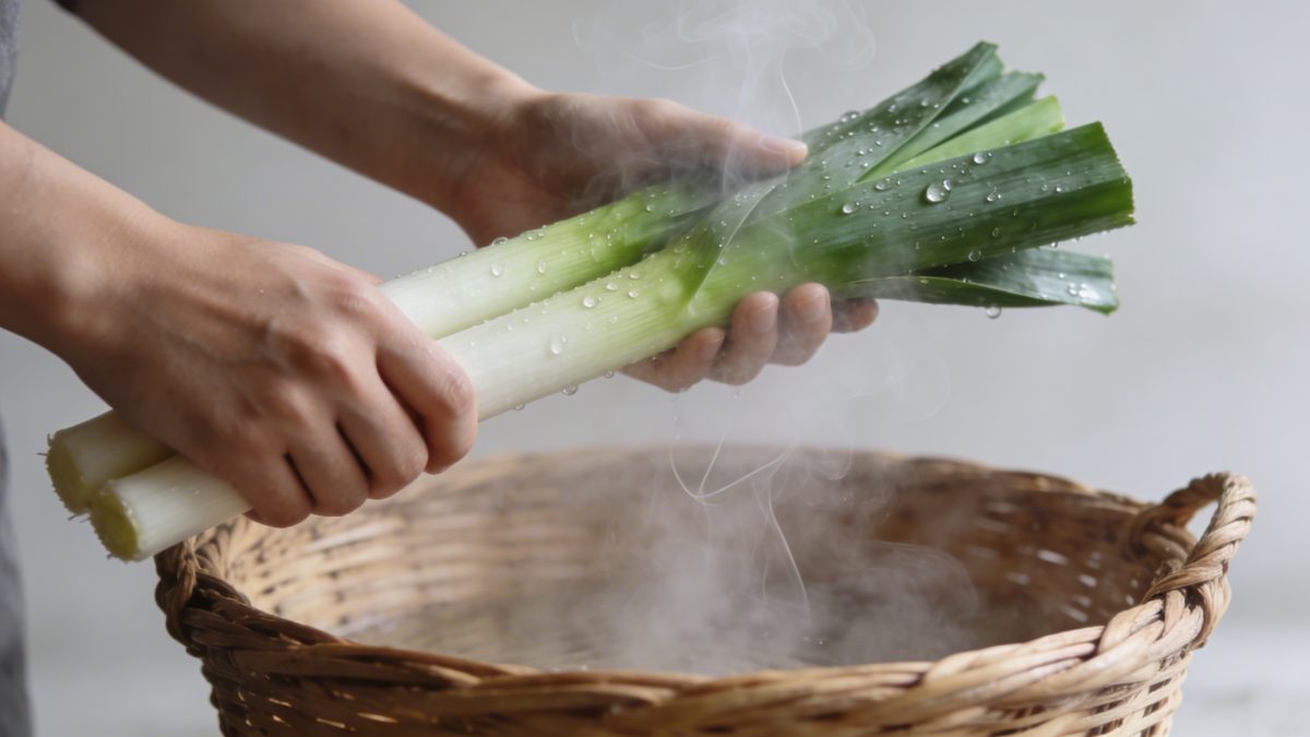 Mains disposant des poireaux sur panier vapeur fumant