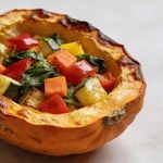 Moitié de courge rôtie garnie de légumes colorés