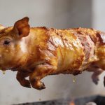 Petit cochon entier dore tournant sur broche
