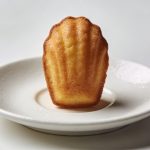 Petite madeleine doree sur soucoupe blanche