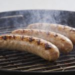 Saucisses de Montbeliard grillees sur barbecue fumant