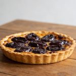 Tarte aux prunes doree sur table en bois