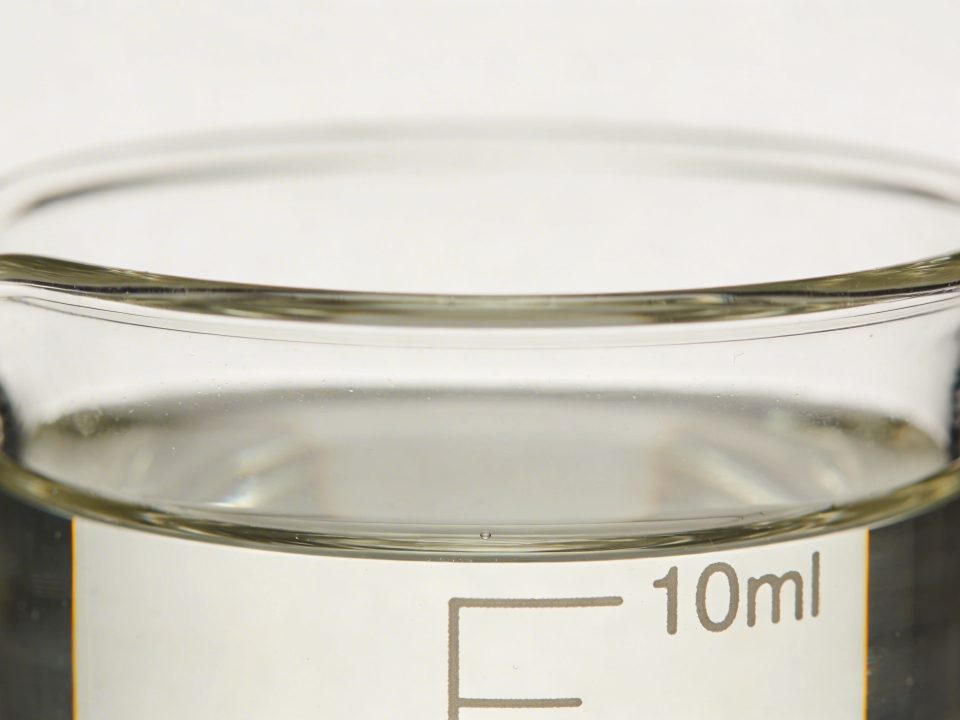 Verre doseur transparent rempli a 10 cl sur fond blanc