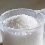 Verre doseur en plastique rempli de sucre blanc