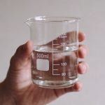 Main tenant un verre doseur transparent rempli deau