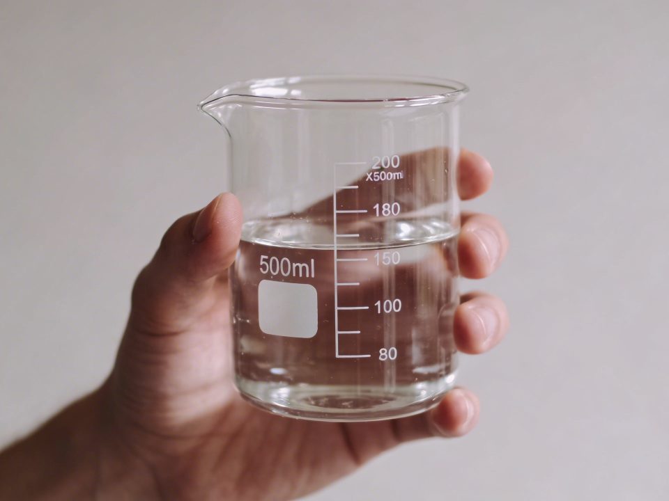 Main tenant un verre doseur transparent rempli deau