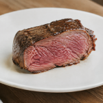 Viande rose epaisse posee sur assiette blanche