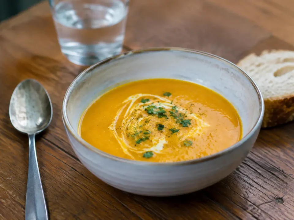 Bol de veloute orange servi sur table en bois