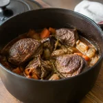 Cocotte en fonte remplie de viande, posee sur bois