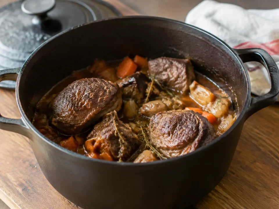 Cocotte en fonte remplie de viande, posee sur bois