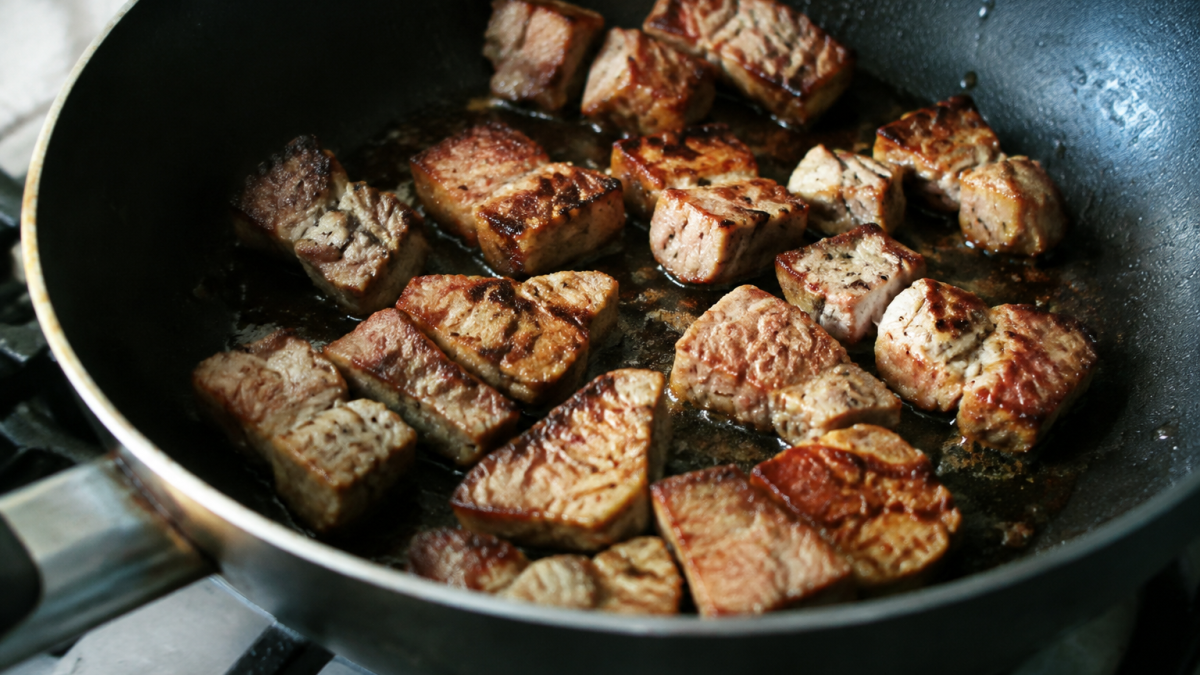 Cubes de porc dores dans une poele noire