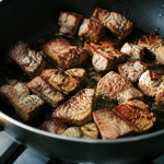 Cubes de porc dores dans une poele noire