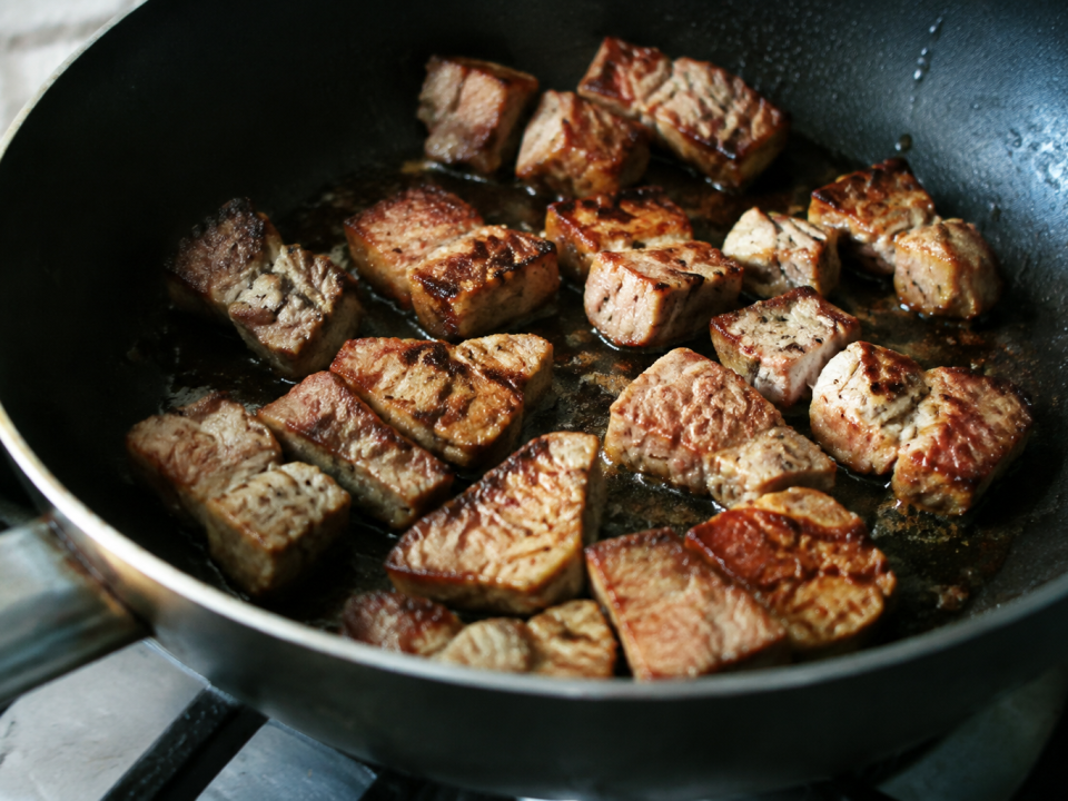 Cubes de porc dores dans une poele noire