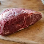 Grand morceau de viande crue sur planche en bois