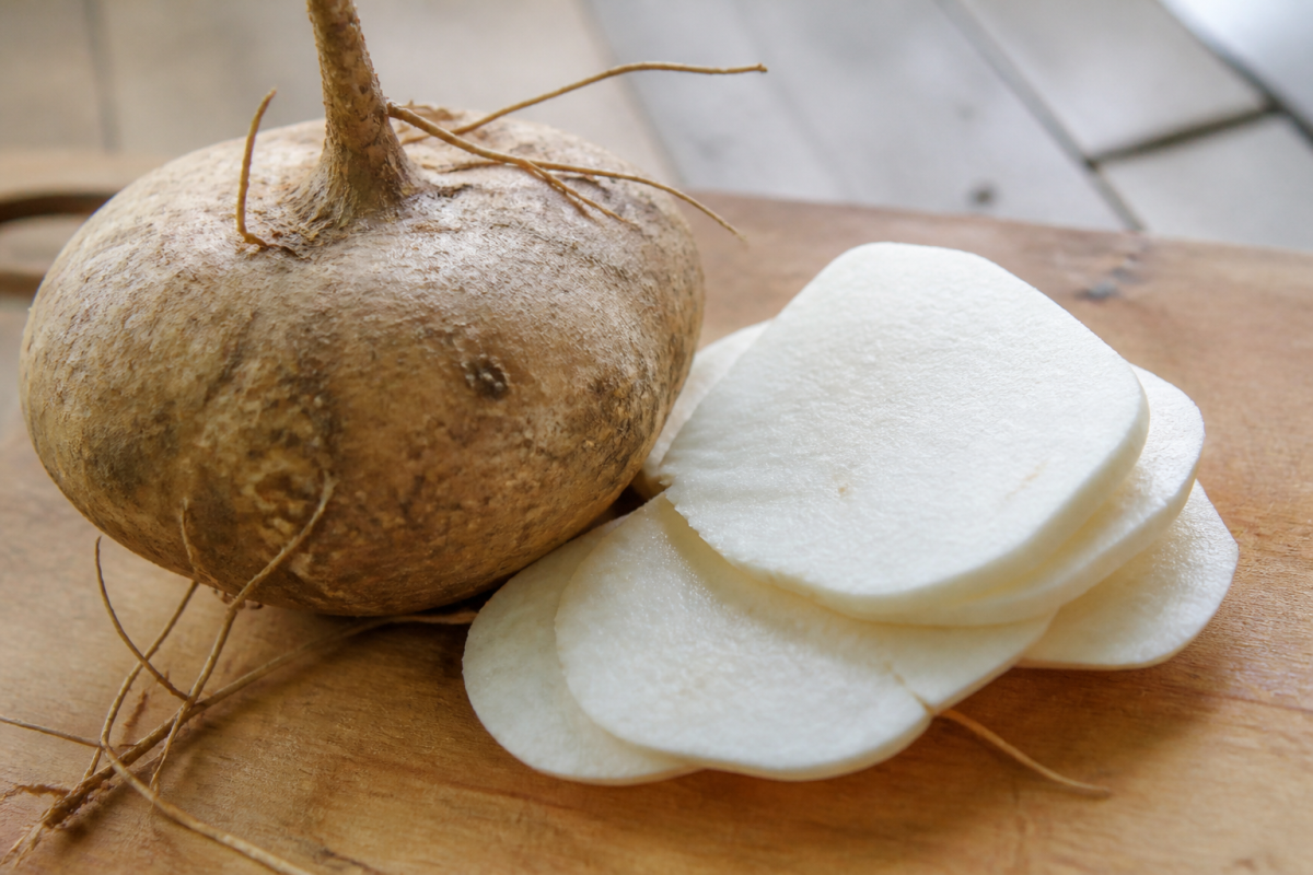 Racine de jicama brune et tranches blanches sur planche