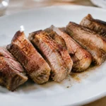 Tranches de viande dorees alignees sur assiette blanche
